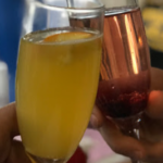 Two people holding glasses of wine and orange juice.